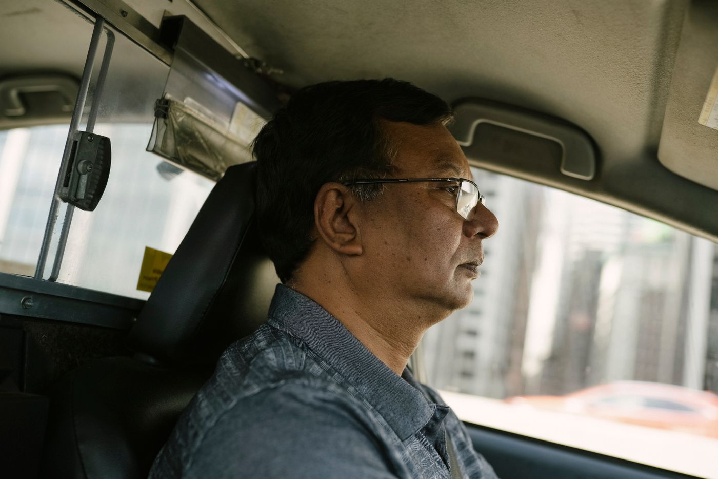 A man at the wheel of a car, looking ahead at the road