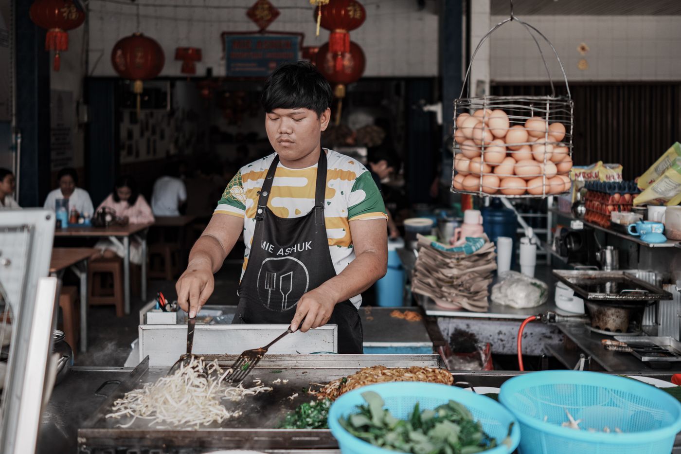 A stall owner frying noodles at a hawker stall