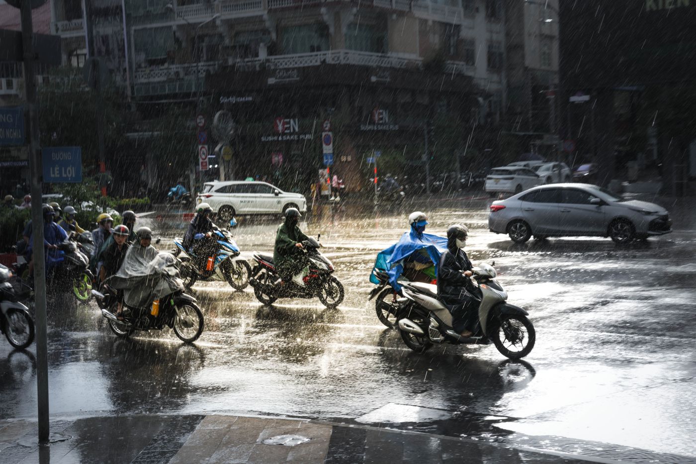 Riders in raincoats crossing a junction in heavy rain